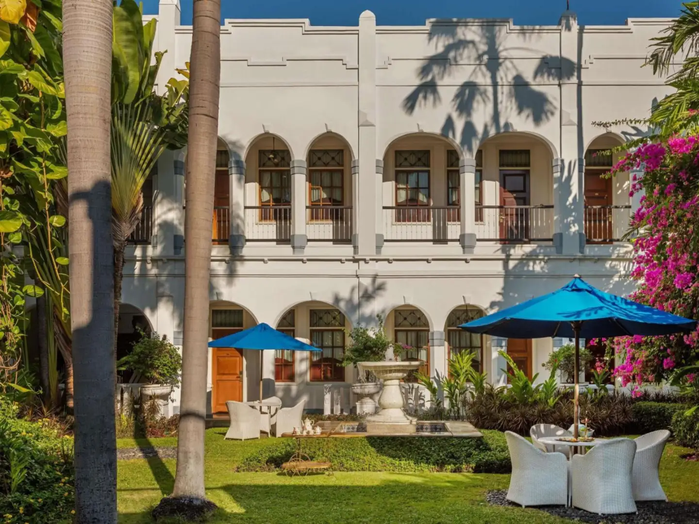 Hotel Majapahit Surabaya MGallery – hôtel à Surabaya, Indonésie – un hôtel avec des chaises et des parasols devant un bâtiment à l'Hotel Majapahit Surabaya MGallery à Surabaya